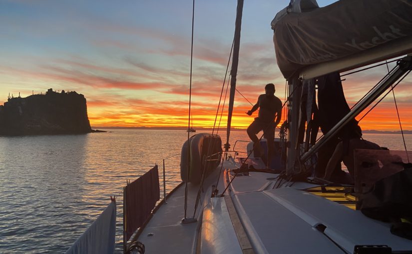 Andy walking on a sailboat with an incredible sunset behind him.